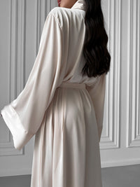 Wrap yourself in elegance with our Long Silky Robe featuring a Shawl Collar and seductive side slits. Crafted from sumptuous silky fabric, this robe offers a perfect blend of sophistication and comfort for your lounging pleasure. Okiya Studio