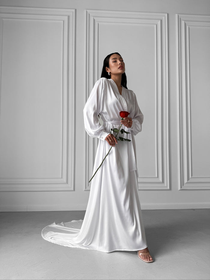 Okiya Studio. Experience the elegance of your bridal morning with our Extra Long Robe. Featuring a tie waist, open front, and long sleeves with button cuffs, this robe is crafted for the perfect blend of comfort and bridal allure.