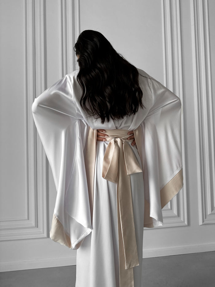 Elevate your loungewear with our White Kimono Robe, featuring silk kimono sleeves, ivory collar trimming, and a matching belt. This long robe embodies classic elegance and comfort. Perfect for any occasion, this exquisite piece is a versatile addition to your wardrobe. Discover timeless sophistication with #SilkKimonoSleeves and #LongRobe refinement